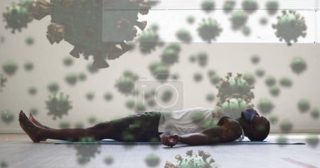 Foto de Imagen de células covid-19 flotando sobre un hombre afroamericano usando mascarilla. Global covid 19 pandemia concepto de imagen generada digitalmente. - Imagen libre de derechos