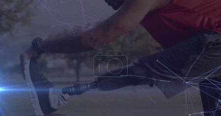 Foto de Imagen de una red de comunicación brillante sobre un atleta masculino con una pierna protésica haciendo ejercicio al aire libre. concepto de tecnología del deporte, logro y comunicación, imagen generada digitalmente. - Imagen libre de derechos