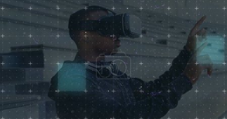 Foto de Senderos de luz sobre la red contra el hombre afroamericano con auriculares vr en la oficina. - Imagen libre de derechos