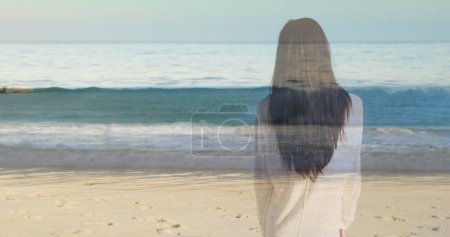 Foto de Mujer de pie en la playa con olas a la vista. - Imagen libre de derechos