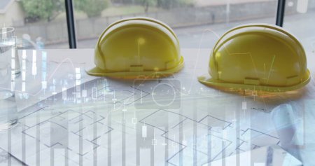 Photo for Safety hats on building plans laid out on a table. - Royalty Free Image