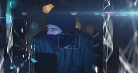 Imagen de interfaz digital con procesamiento de datos sobre hacker masculino en pasamontañas usando laptop. Concepto de tecnología de red informática global imagen generada digitalmente.