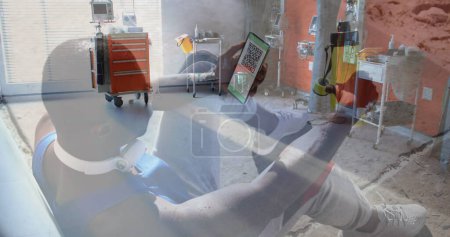 Foto de Composición de hombre afroamericano sosteniendo un teléfono inteligente con código qr en la pantalla contra el hospital. covid-19 certificado de vacunación y concepto de pase sanitario - Imagen libre de derechos