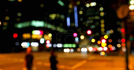 Blurred city lights create a vibrant backdrop at night. The image captures the bustling atmosphere of urban nightlife.