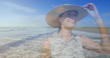 Mujer caucásica en un sombrero camina por la playa.