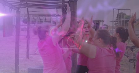 Photo for Image of light spots over diverse women at obstacle course high fiving. Global sport, health, fitness and digital interface concept digitally generated image. - Royalty Free Image