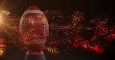 Foto de Imagen de partículas naranjas brillantes moviéndose sobre la pelota de rugby. concepto de deporte y competición, imagen generada digitalmente. - Imagen libre de derechos