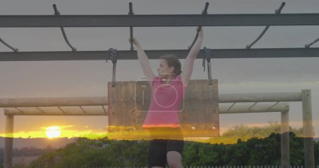 Téléchargez les photos : Image du coucher du soleil sur une femme caucasienne suspendue à un parcours d'obstacles. Concept mondial de sport, de santé, de fitness et d'interface numérique image générée numériquement. - en image libre de droit