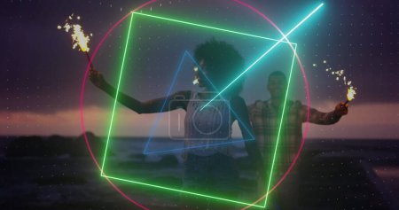 Image of neon scanner processing data over couple celebrating with sparklers on beach. holiday, celebration and technology concept, digitally generated image.