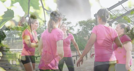 Photo for Image of leaves over diverse women at obstacle course high fiving. Global sport, health, fitness and digital interface concept digitally generated image. - Royalty Free Image