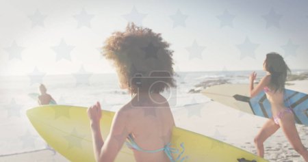 Sterne und amerikanische Flagge wehen gegen eine Gruppe von Freunden mit Surfbrett am Strand. Amerikanische Unabhängigkeit patriotisches Urlaubskonzept