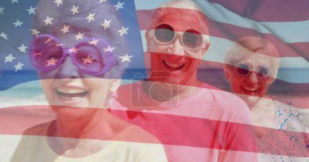 Foto de Imagen de la bandera de EE.UU. sobre amigos mayores caucásicos en la playa en verano. EE.UU., patriotismo americano, bandera nacional y concepto de estilo de vida imagen generada digitalmente. - Imagen libre de derechos