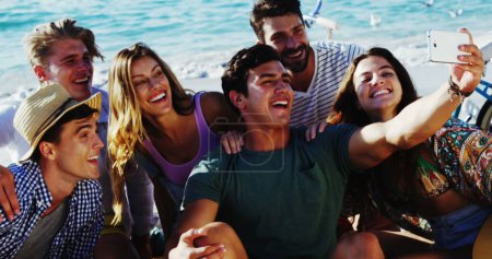 Photo for Image of emoji icons flying up with a group of young Caucasian friends taking a selfie on a beach in the background 4k - Royalty Free Image