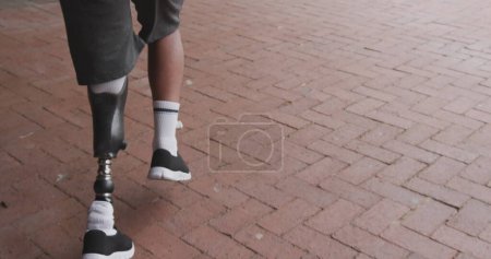 Téléchargez les photos : Image de la carte du monde sur l'homme afro-américain handicapé avec jambe artificielle en cours d'exécution. Journée internationale des personnes handicapées concept image générée numériquement. - en image libre de droit