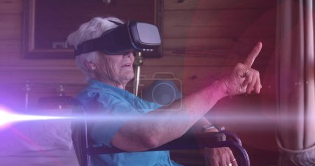 Image of light moving over senior woman in wheelchair using vr headset. retirement, domestic life and hope concept digitally generated image.
