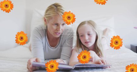 Image of flowers over caucasian mother and daughter reading book in bed. family life, childhood, love and care concept digitally generated image.
