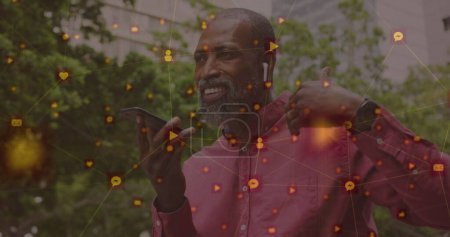 Bild von Netzwerken mit digitalen Ikonen über einem afrikanisch-amerikanischen Mann, der sein Smartphone in der Stadt benutzt. globales soziales Netzwerk, Kommunikations- und Verbindungskonzept digital generiertes Bild.
