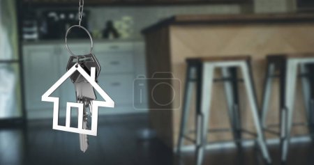 Photo for Image of silver house keys and house shaped key fob hanging over an out of focus open plan kitchen 4k - Royalty Free Image