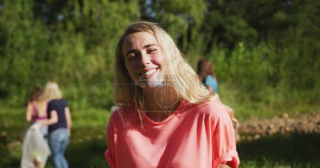 Téléchargez les photos : Jeune femme caucasienne sourit vivement à l'extérieur, avec un espace de copie. Les amis profitent d'une journée ensoleillée dans un cadre verdoyant. - en image libre de droit