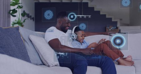 Photo for Image of diverse data over happy african american father and son using tablet. family, togetherness, spending time with technology concept digitally generated image. - Royalty Free Image