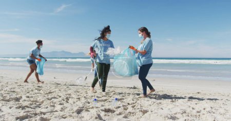 Foto de Los voluntarios limpian una playa, con espacio para copias. Diversos grupos de mujeres participan en un esfuerzo de conservación ambiental al aire libre. - Imagen libre de derechos