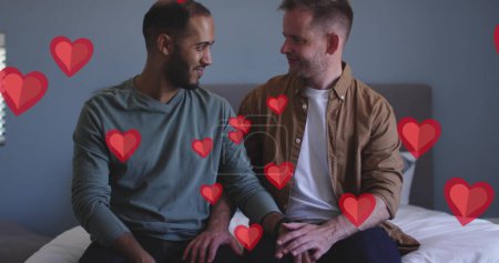 Téléchargez les photos : Image de coeurs rouges sur divers couples masculins assis sur le lit. Saint Valentin, concept d'amour et de célébration image générée numériquement. - en image libre de droit