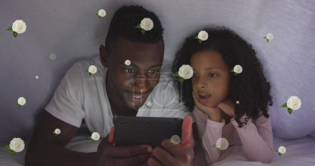 Téléchargez les photos : Image de roses sur heureux père afro-américain et sa fille en utilisant une tablette au lit. vie de famille, enfance, amour et concept de soins image générée numériquement. - en image libre de droit