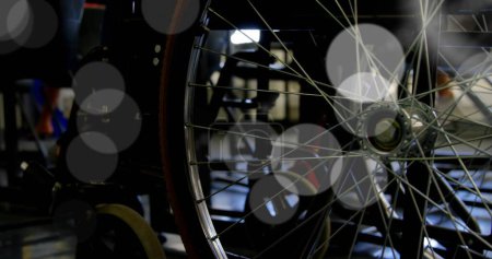 Foto de Primer plano de una rueda de bicicleta en una habitación débilmente iluminada. El enfoque en los intrincados radios añade una estética técnica al entorno. - Imagen libre de derechos