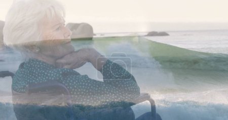 Imagen de paisaje marino sobre mujer cuacasiana discapacitada sentada en silla de ruedas. Día internacional de las personas con discapacidad concepto de imagen generada digitalmente.