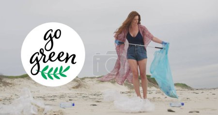 Photo for Image of go green text and logo over smiling caucasian woman picking up rubbish from beach. eco conservation volunteer month digitally generated image. - Royalty Free Image