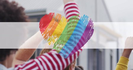 Image of rainbow heart over hands of diverse protesters. lgbt rights and equality concept digitally generated image.