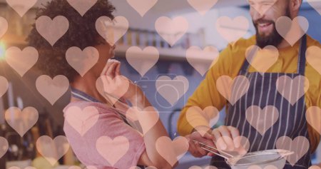 Téléchargez les photos : Image de coeurs sur divers couples préparant des repas dans la cuisine. Relation, amour, romance et style de vie concept image générée numériquement. - en image libre de droit