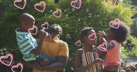 Photo for Image of hearts over happy african american family making soap bubbles in garden. family, love and communication technology concept digitally generated image. - Royalty Free Image
