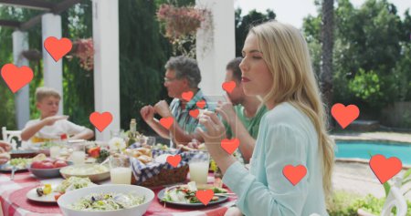 Téléchargez les photos : Image de cœurs sur la famille caucasienne mangeant dans le jardin. famille, vie familiale, amour et concept de soins image générée numériquement. - en image libre de droit