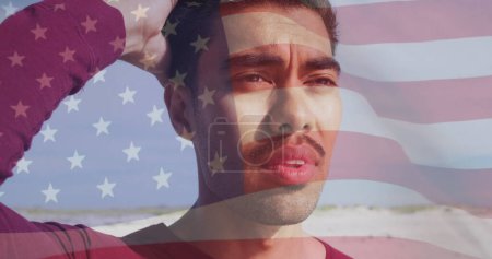 Téléchargez les photos : Image du drapeau des États-Unis d'Amérique et de l'homme biracial sur la plage. Patriotisme américain, diversité et concept de tradition image générée numériquement. - en image libre de droit