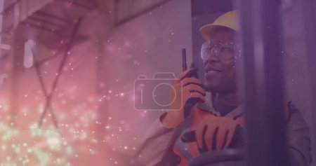 Téléchargez les photos : Image d'un travailleur afro-américain parlant dans un entrepôt sur des spots lumineux. Journée du travail et concept de célébration image générée numériquement. - en image libre de droit