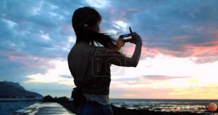 Foto de Imagen de iconos emoji volando de izquierda a derecha con una joven mujer caucásica tomando una selfie en una playa en el fondo 4k - Imagen libre de derechos