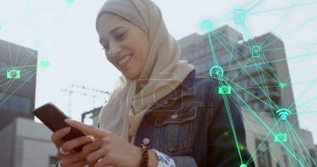 Téléchargez les photos : Image de connexions et de traitement de données sur femme biraciale dans le hijab à l'aide d'un smartphone. Concept global d'entreprise, de finance, d'informatique en nuage et de traitement des données image générée numériquement. - en image libre de droit