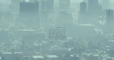 Téléchargez les photos : Un paysage urbain est obscurci par une épaisse couche de smog, signalant les problèmes de pollution. La brume met en lumière les préoccupations environnementales en milieu urbain. - en image libre de droit