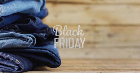 Image of black friday text over denim trousers on wooden background. Sales, retail, shopping, digital interface, communication, computing and data processing concept digitally generated image.