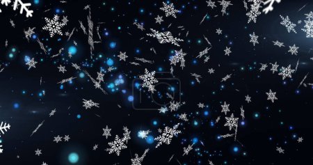 Téléchargez les photos : Image numérique de flocons de neige tombant sur des taches bleues de lumière sur fond noir. Noël fête et concept de célébration - en image libre de droit