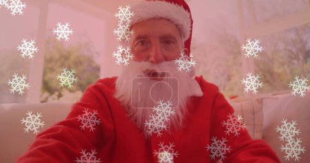 Téléchargez les photos : Image de neige tombant sur un homme souriant portant un costume de Père Noël et ayant un appel d'image. Noël, hiver, tradition et concept de célébration image générée numériquement. - en image libre de droit