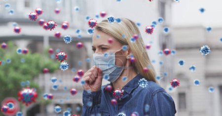 Photo for Image of virus cells over caucasian female wearing face mask coughing. global covid 19 pandemic, health and science concept digitally generated image. - Royalty Free Image