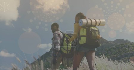 Photo for Multiple light spots and abstract geometric shapes floating against african american couple hiking. hiking and exploration concept - Royalty Free Image