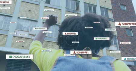 Image of social media notifications over african american woman raising fist in city street. global communication technology and social network concept digitally generated image.