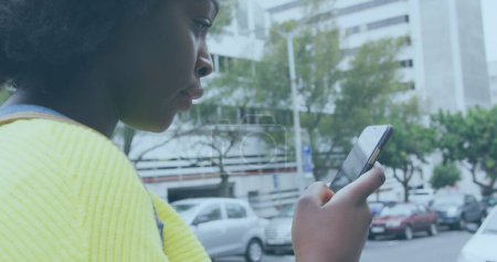 Image of social media notifications over happy african american woman using smartphone in street. global communication technology and social network concept digitally generated image.