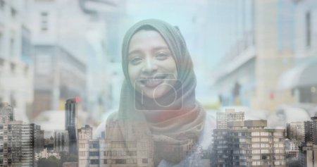 Photo for Image of asian woman in hijab smiling over cityscape. global business, communication and finance concept digitally generated image. - Royalty Free Image