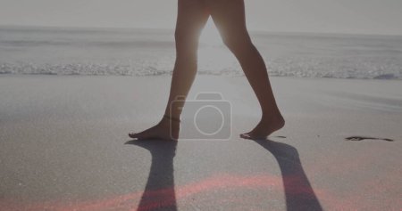 Image of light spots over caucasian woman walking at beach. Holidays and digital interface concept digitally generated image.