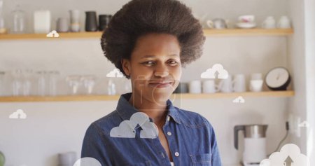 Téléchargez les photos : Image d'icônes de nuages sur un sourire afro-américain. Cloud computing mondial, médias sociaux, réseaux, interface numérique et concept de traitement de données image générée numériquement. - en image libre de droit