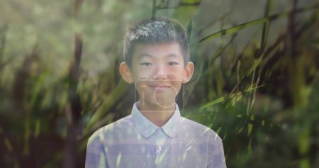 Photo for Image of smiling asian boy over moving grass. leisure and wellbeing concept digitally generated image. - Royalty Free Image